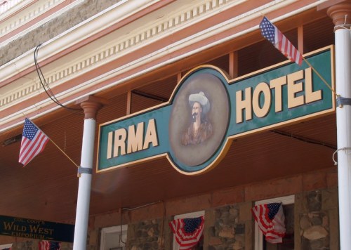 Sign for the Irma Hotel featuring a portrait and American flags, set against a historic building backdrop.