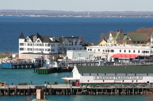 A scenic view of a waterfront area with colorful buildings, docks, and a calm blue lake in the background.