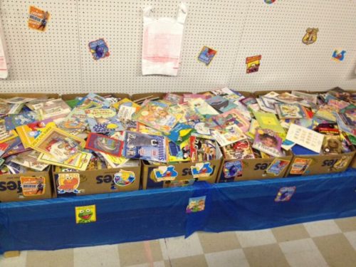 A colorful display of children's books piled in boxes on a table, surrounded by playful decorations.