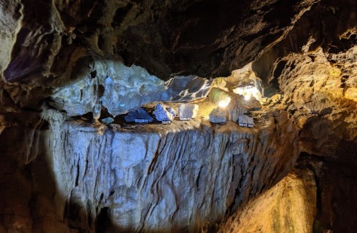 A dimly lit cave interior with rocky formations and illuminated areas highlighting the textures of the stone.