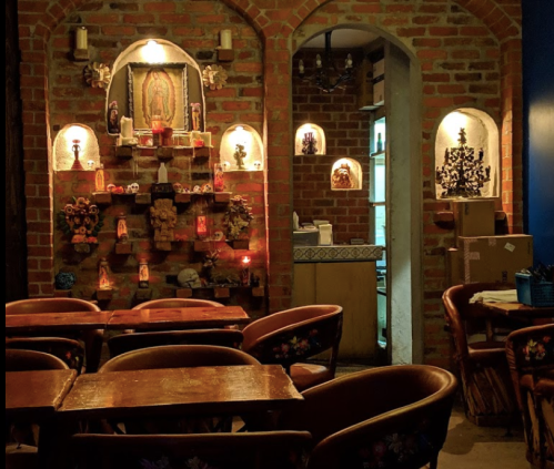 Cozy restaurant interior with brick walls, decorative shelves, and wooden tables, creating a warm ambiance.