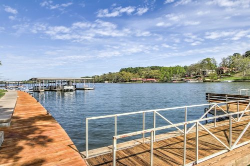 Scenic view of a calm lake with docks, wooden walkways, and lush greenery under a blue sky with scattered clouds.