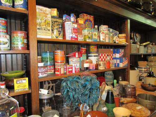 A vintage display of colorful food cans and jars on wooden shelves, showcasing various retro packaging and kitchen items.