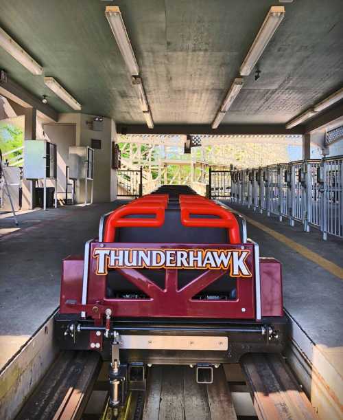 View of the Thunderhawk roller coaster train at the loading station, with empty queue lines in the background.