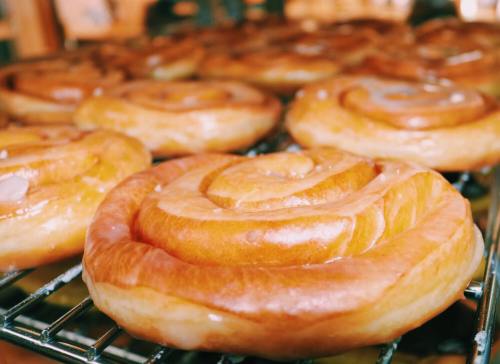 Freshly baked cinnamon rolls glistening with icing, arranged on a cooling rack.