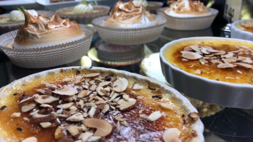 Close-up of creamy desserts topped with toasted almonds, with meringue-topped treats in the background.