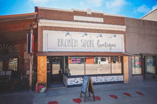 Exterior of a boutique named "Broken Spoke Boutique," featuring a sign and a welcoming entrance.