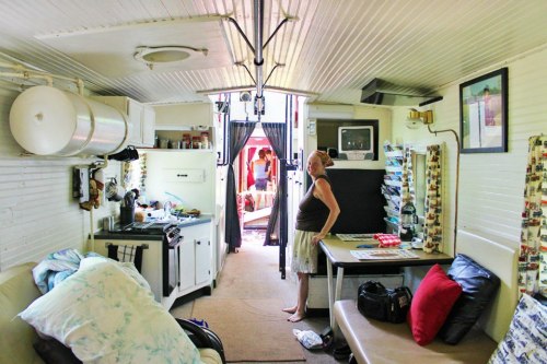 A cozy interior of a small living space with a kitchen, seating area, and a person standing near the entrance.