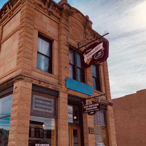 Historic building with a sign for an ice cream shop, featuring stone architecture and a clear blue sky.