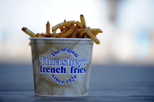 A cup of Thrasher's French fries, featuring golden, crispy fries in a branded container.