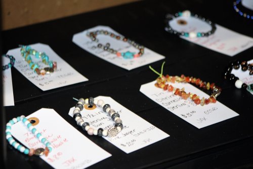 A display of handmade bracelets on tags with prices, featuring various beads and colors.
