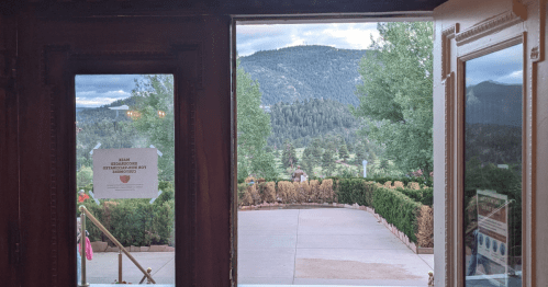 View from an open doorway showing a landscaped garden and mountains in the background under a cloudy sky.