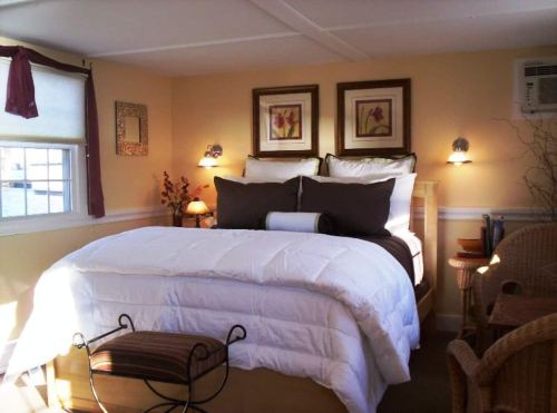 Cozy bedroom with a large bed, decorative pillows, framed art, and warm lighting.