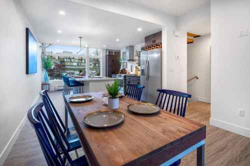 Modern kitchen and dining area with a wooden table, blue chairs, and a view of the outdoors through large windows.
