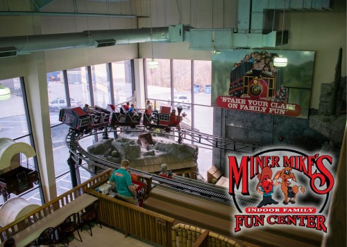A view of an indoor family fun center with a train track and a colorful sign for Miner Mike's Fun Center.
