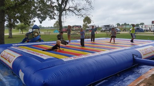 A colorful inflatable bounce house with children playing and jumping on it in a park setting.