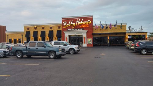Exterior view of Bobby Hebert's Cajun Cannon restaurant, featuring a parking lot and flags outside.
