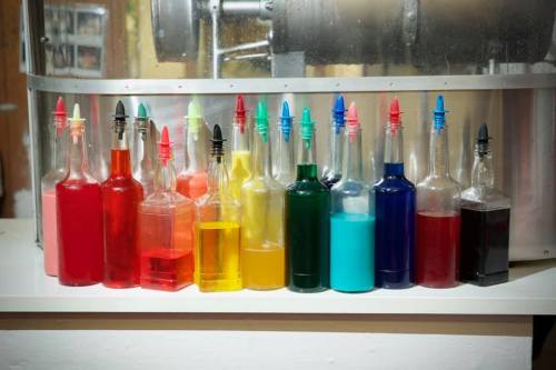 A row of colorful bottles filled with various liquids, arranged on a shelf.