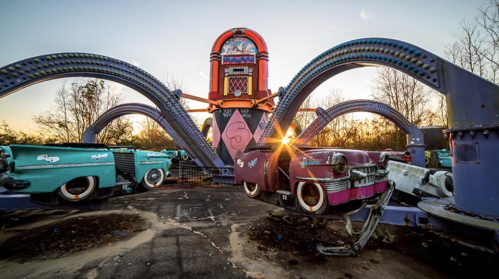 Abandoned amusement park ride with colorful cars and an octopus-like structure, illuminated by sunset.