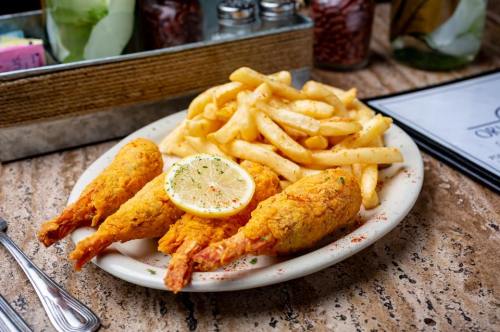 A plate of golden fried shrimp with a lemon slice, served alongside crispy French fries.