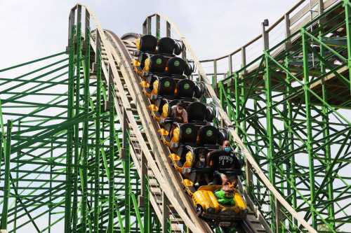 A roller coaster descends a steep track with riders enjoying the thrill of the ride.