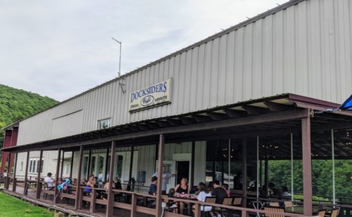 A restaurant named "Docksiders" with outdoor seating, surrounded by greenery and people dining on the porch.