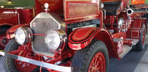 A vintage red fire truck with ornate detailing, showcasing its classic design and large wheels.