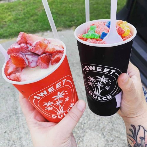 Two colorful cups of dessert: one with strawberries and cream, the other with colorful candy toppings.