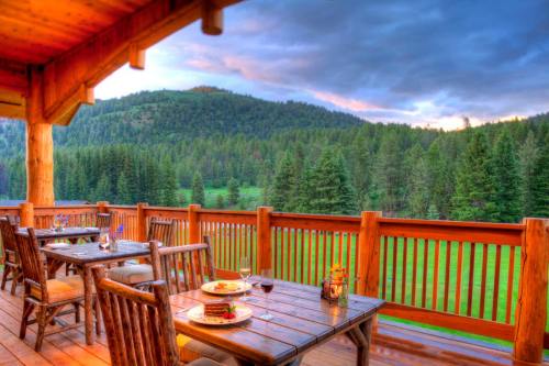 A scenic view from a wooden deck overlooking a lush green landscape and mountains, with dining tables set for a meal.
