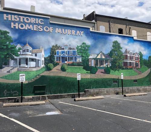 Mural depicting historic homes of Murray, featuring colorful houses and greenery, with a blue sky above.