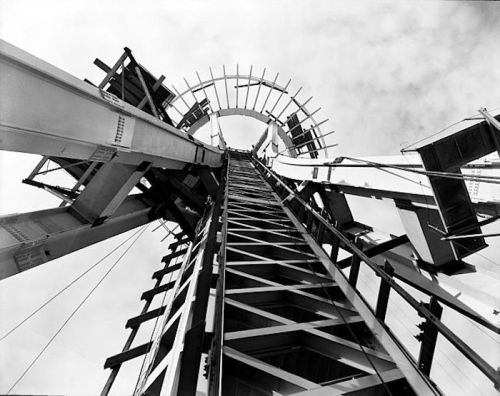 Black and white image of a tall structure viewed from below, showcasing its metal framework and circular top.