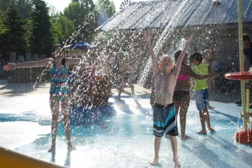 Children playing in a splash pad, joyfully enjoying water sprays on a sunny day.