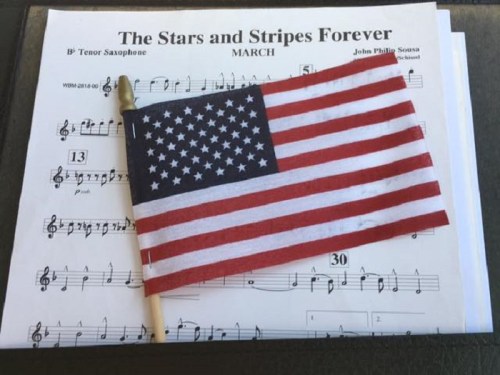A small American flag rests on sheet music for "The Stars and Stripes Forever" by John Philip Sousa.