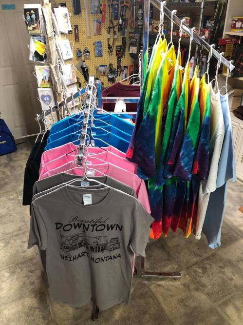 A display of colorful t-shirts and tie-dye shirts hanging on racks in a shop.
