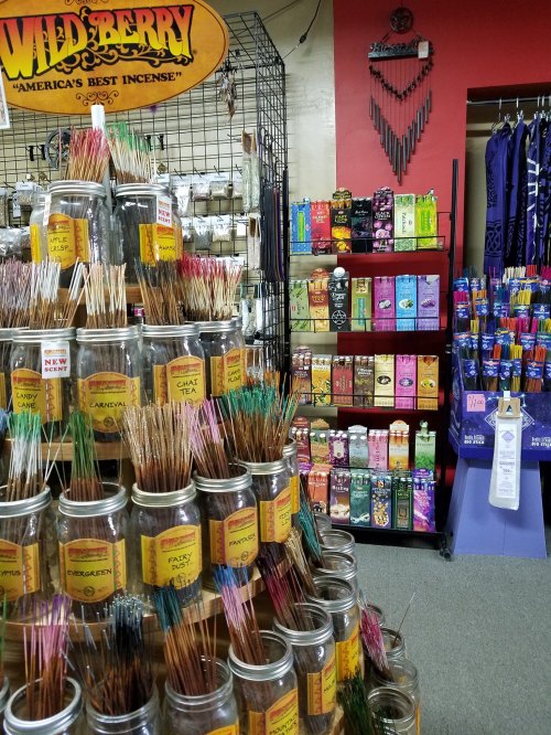 A display of colorful incense sticks in jars, with various incense packs on shelves in a shop.