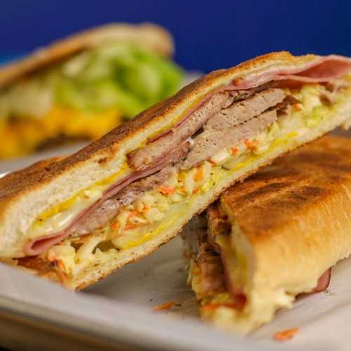 A close-up of a sandwich filled with layers of meat, cheese, and vegetables, served on a plate.