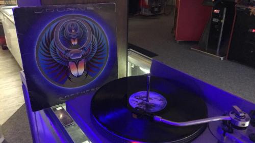A vinyl record of Journey's "Captive" on a turntable, with the album cover displayed beside it.