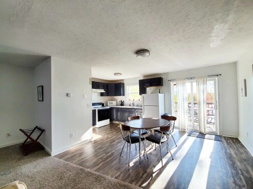 Bright, modern kitchen and dining area with a round table, black cabinets, and sliding glass doors to an outdoor space.