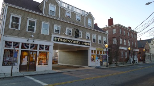 A street view of Thames Street Landing, featuring a building with shops and decorative awnings, in a quaint town setting.