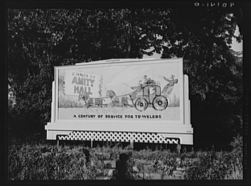 Billboard advertising "Amity Hall," featuring a vintage tractor and the text "A Century of Service for Travellers."