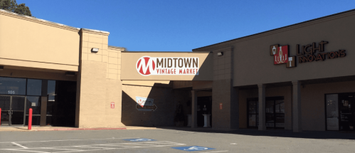 Sign for Midtown Vintage Market on a storefront, with another business, Light Innovations, visible nearby. Clear blue sky.