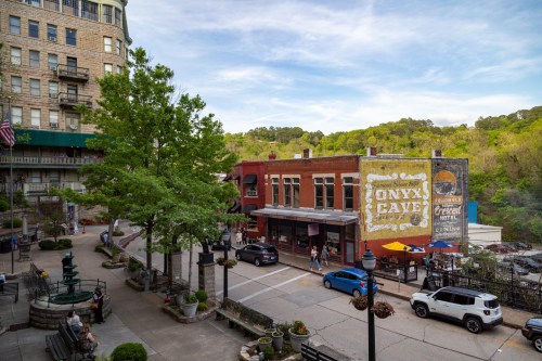 A vibrant street scene featuring shops, greenery, and a mural of "Onyx Cave" in a scenic town setting.