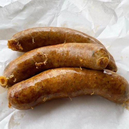 Three cooked sausages resting on white parchment paper.