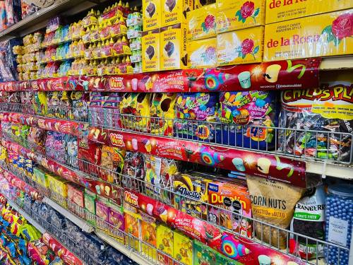A colorful display of various candies and snacks on shelves in a grocery store.