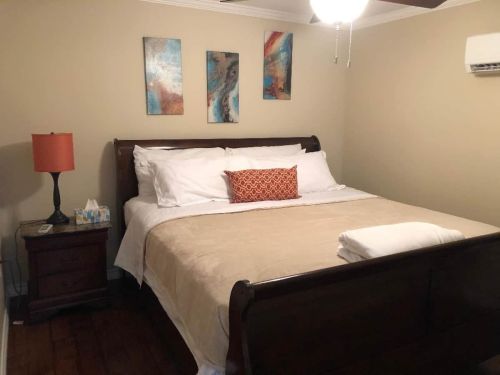 Cozy bedroom with a wooden bed, decorative pillows, nightstand, lamp, and abstract wall art.