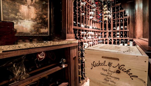 A wine cellar featuring wooden racks filled with bottles and a wooden crate labeled "Nickel & Nickel."