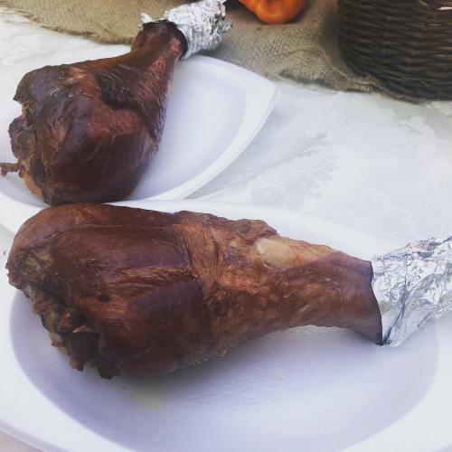 Two smoked turkey legs on white plates, with a rustic table setting in the background.