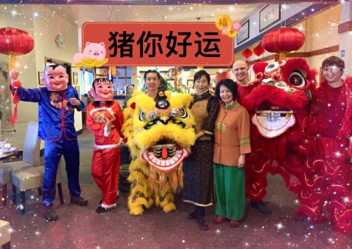 A group of people in colorful costumes celebrating with lion dancers and festive decorations in a restaurant.