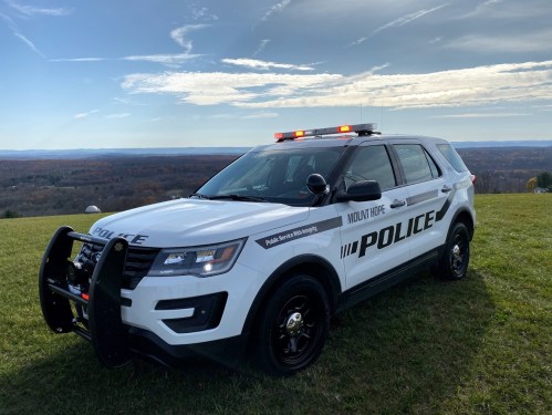 A Mount Hope police SUV parked on a grassy hill with a scenic view of rolling hills in the background.