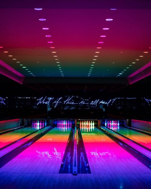 A vibrant bowling alley with colorful lights and neon text on the wall, creating a lively atmosphere.